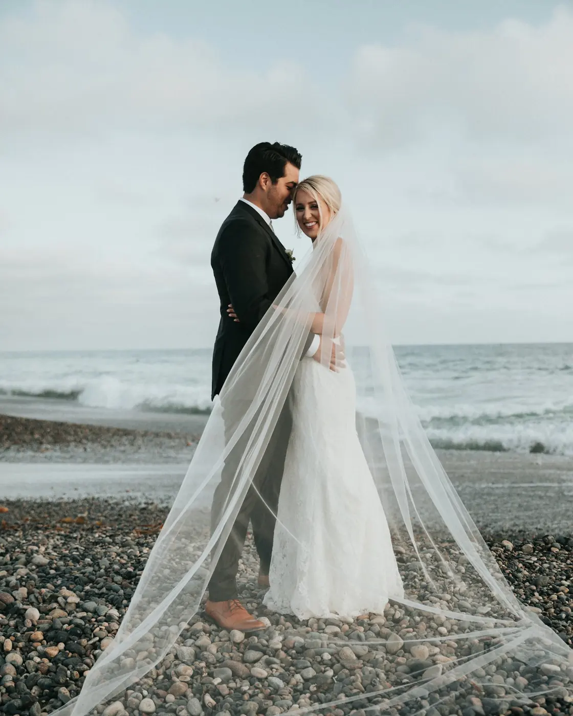 Bride in a veil photographed on a pebble beach